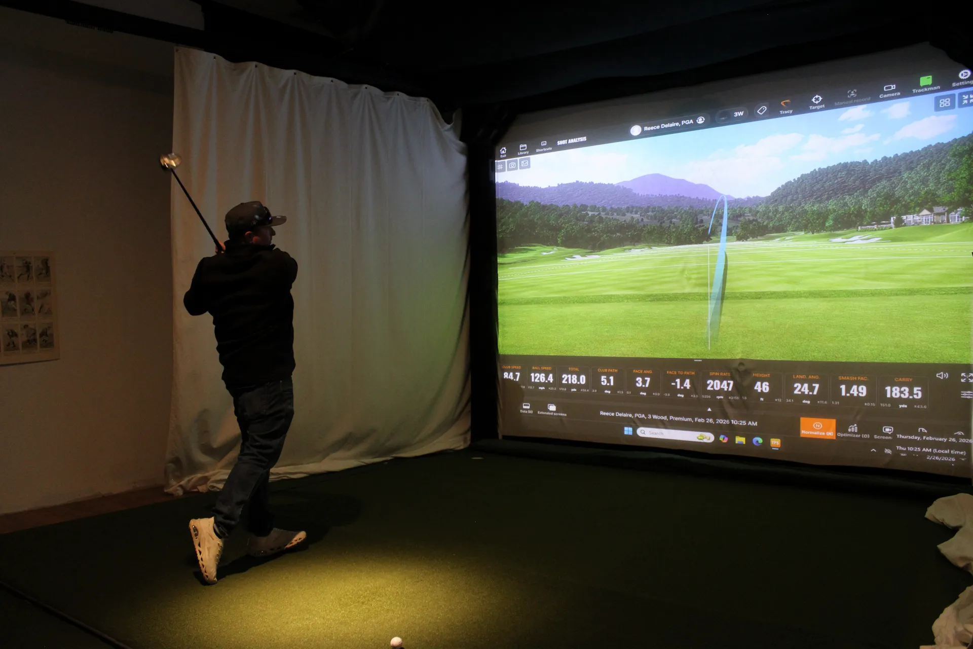 Player in black hoodie hitting a shot on a mountain course with TrackMan shot data overlay