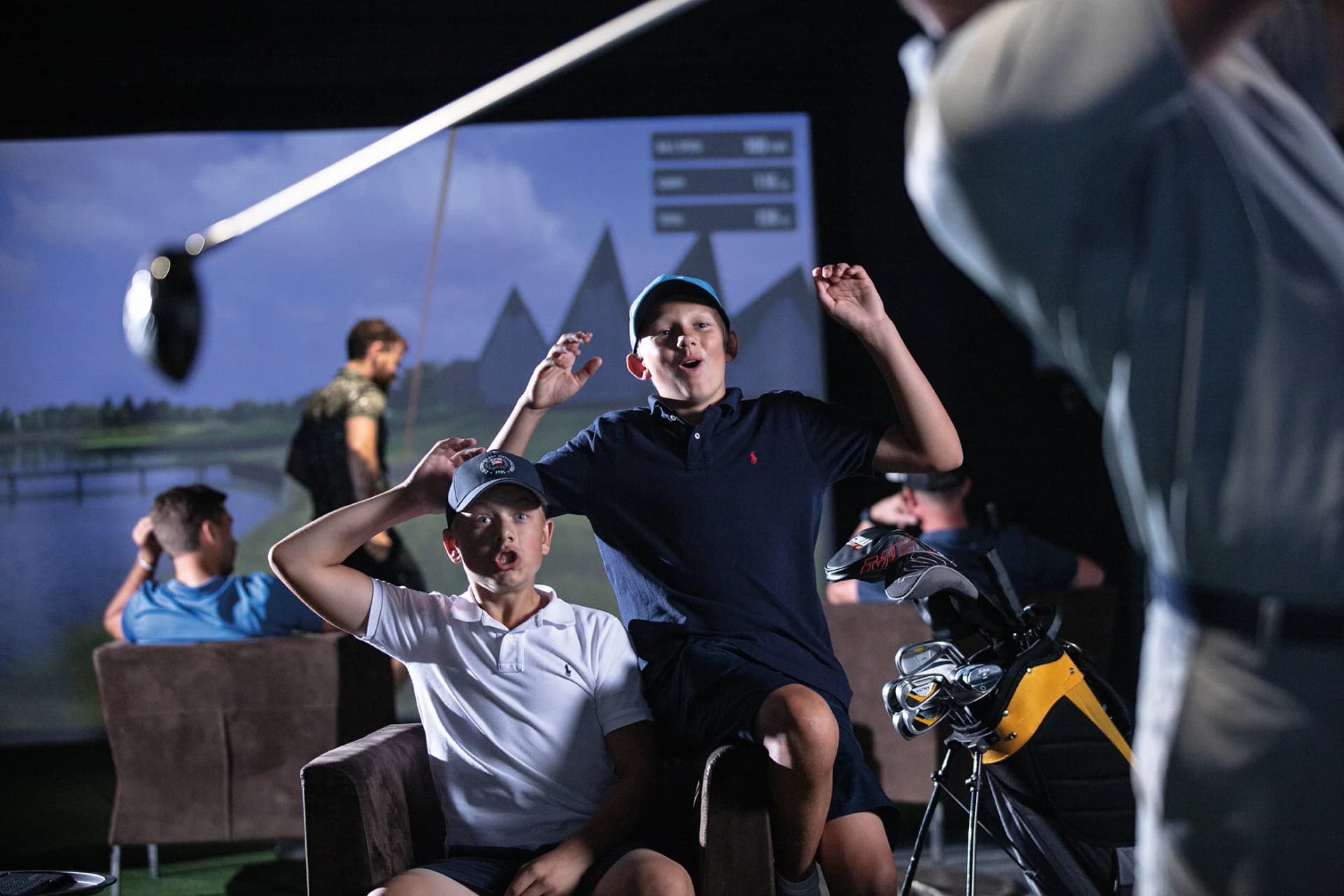 Children cheering and celebrating during a birthday party at a TrackMan simulator
