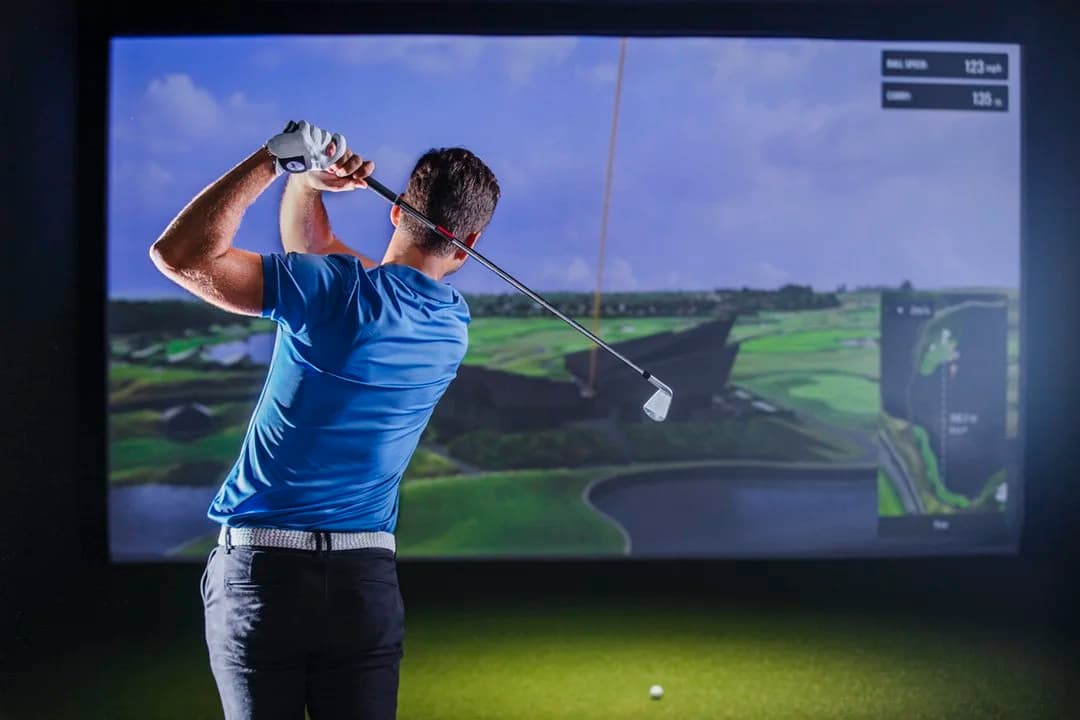 Golfer taking a competitive swing in a TrackMan simulator during league play
